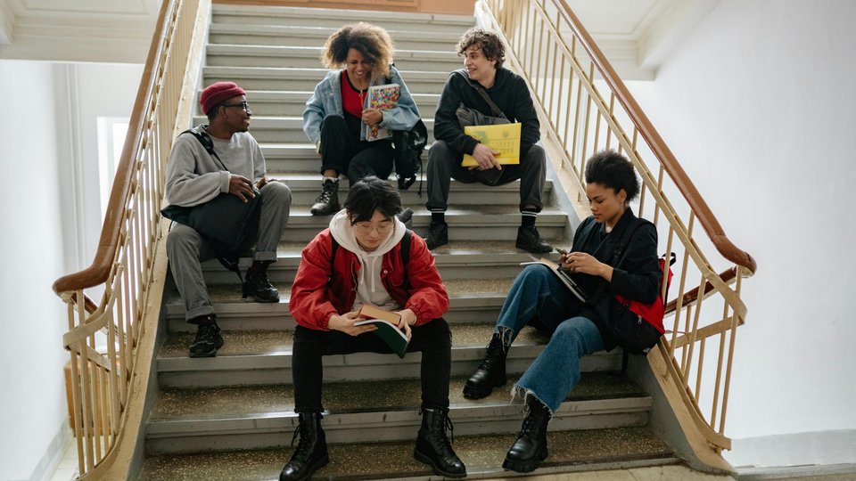 Studierende, die lernend auf einer Treppe sitzen
